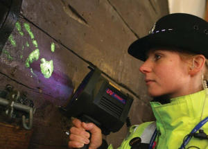 Police Officer using Labino UV Light to highlight SmartWater handprints on wooden door.